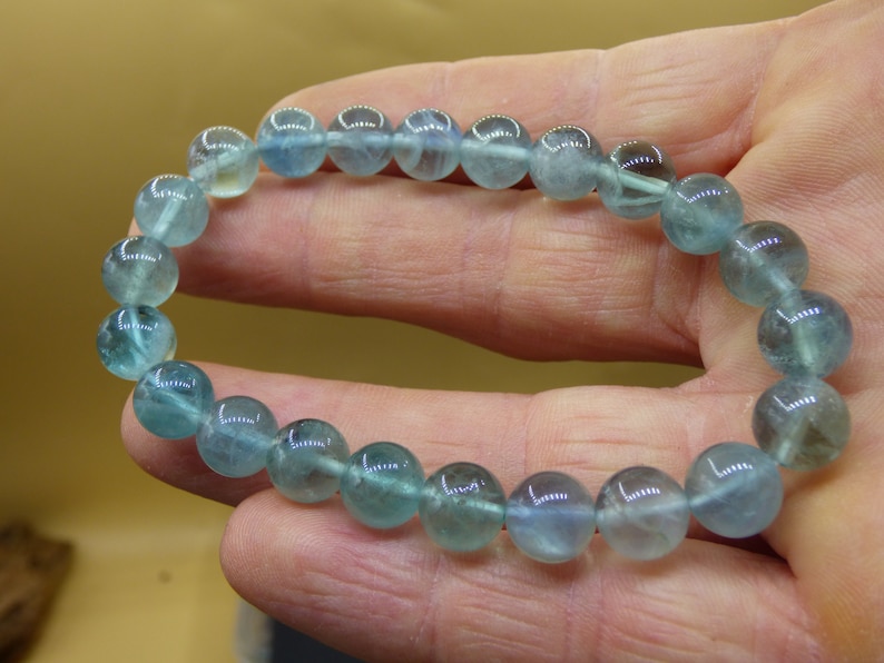 May include: A bracelet made of light blue gemstone beads. The beads are round and have a slight shimmer to them.