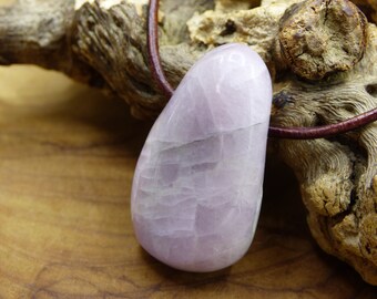 May include: A pale pink, teardrop-shaped gemstone pendant on a brown leather cord. The pendant has a smooth, polished surface with visible striations.
