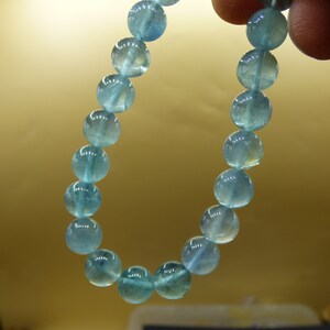 May include: A light blue gemstone bracelet with round beads.