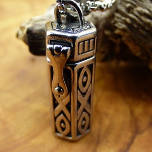 Op de afbeelding: Een zilveren ketting met een gedetailleerd, versierd hanger. De hanger is gevormd als een klein doosje met een scharnierend deksel. De hanger is bevestigd aan een zilveren ketting.