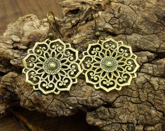 Könnte beinhalten: Ein Paar goldfarbene Ohrringe mit einem filigranen, komplizierten Design. Die Ohrringe haben ein kreisförmiges Mandala-artiges Muster mit einem kleineren, sternförmigen Zentrum.
