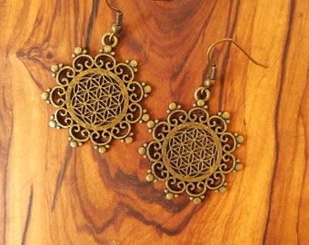 Könnte beinhalten: Ein Paar antikgoldene Ohrringe. Jeder Ohrring hat ein kreisförmiges Design mit einem filigranen Rand und einem geometrischen Muster in der Mitte. Die Ohrringe werden auf einer Holzoberfläche präsentiert.