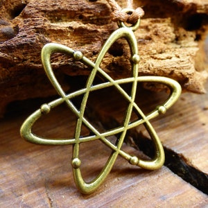 May include: A gold-toned atom pendant necklace with a brown cord. The atom is a stylized design with a central circle and orbiting electrons.