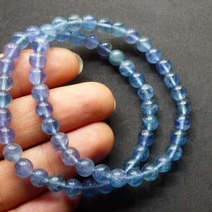 May include: A blue gemstone bracelet with round beads. The beads are a gradient of light blue to dark blue.