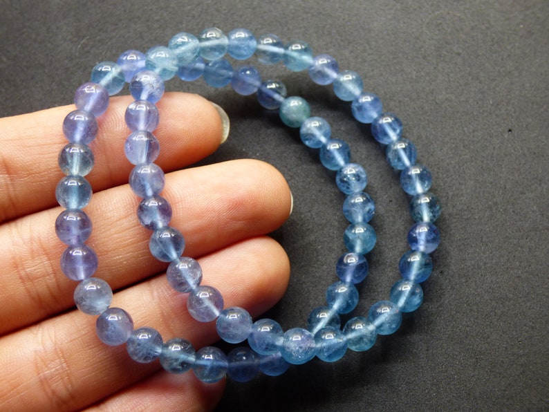 May include: A blue gemstone bracelet with round beads. The beads are a gradient of light blue to dark blue.