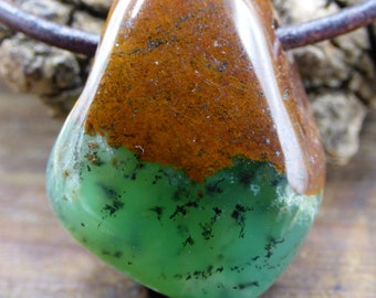 May include: A green and brown polished stone pendant with black flecks. The stone is teardrop shaped and has a smooth, glossy finish.