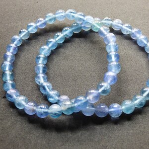 May include: Two blue gemstone bracelets with round beads. The bracelets are made of light blue and dark blue beads.