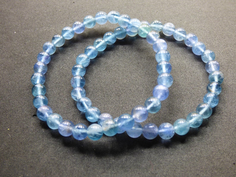 May include: Two blue gemstone bracelets with round beads. The bracelets are made of light blue and dark blue beads.