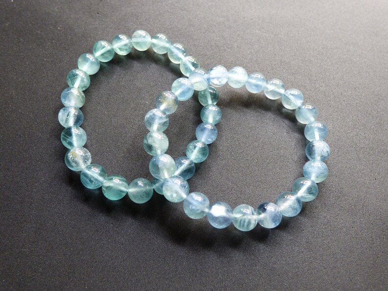 May include: Two light blue gemstone bracelets with round beads.