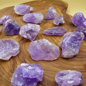 Könnte beinhalten: Eine Sammlung roher Amethystkristalle in verschiedenen Größen und Formen. Die Kristalle sind tiefviolett und haben eine natürliche, raue Textur.