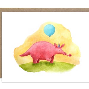 Può includere: Un'illustrazione ad acquerello di un formichiere rosa che indossa un cappello da festa e tiene un palloncino blu. Il formichiere è in piedi su un pezzo di erba verde con uno sfondo giallo.