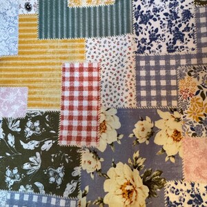 Op de afbeelding: Een patchworkstof met een verscheidenheid aan prints, waaronder geel-witte strepen, rood-wit gingham, blauw-witte bloemmotieven, groen-witte botanische prints en grote cr&egrave;mekleurige bloemen op een blauwe achtergrond.