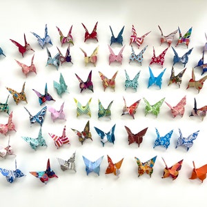 May include: A collection of colorful origami butterflies, each folded from patterned paper, displayed on a white background.