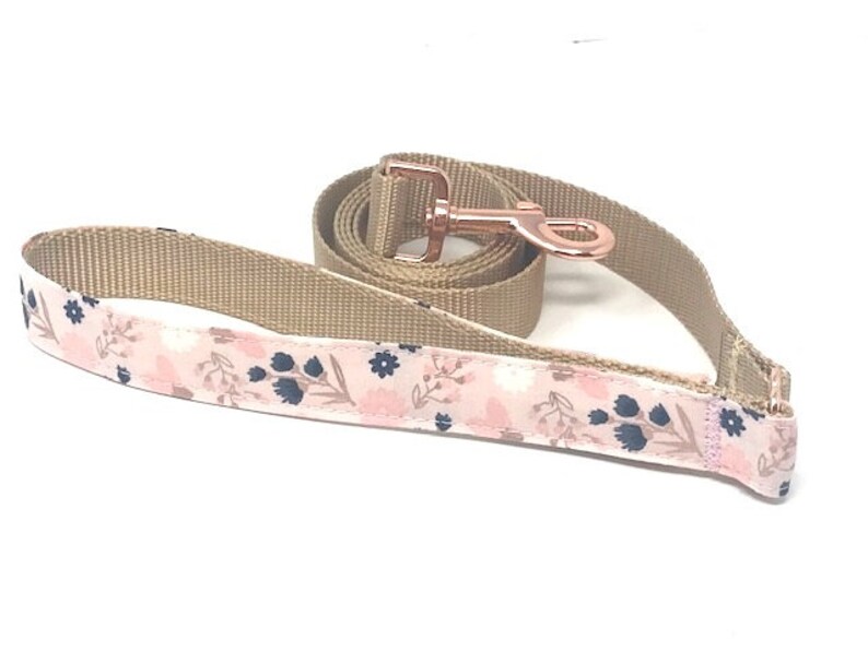 May include: A pink and brown dog lead with a floral pattern and a rose gold metal clip.