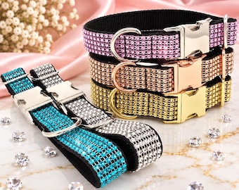 Puede incluir: Una colección de cinco collares para mascotas con bandas de tela negra incrustadas con filas de brillantes pedrería en rosa, oro rosa, oro, turquesa y transparente. Cada collar incluye una hebilla metálica y una anilla en forma de D.