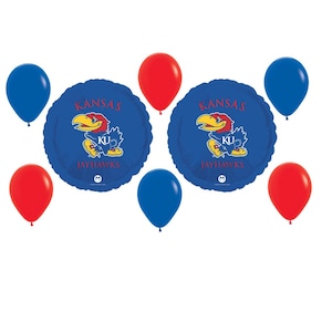 May include: A collection of blue and red balloons, including two round blue balloons with a Kansas Jayhawks logo. The balloons are arranged against a white background, suitable for a party or celebration.