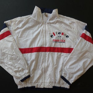 May include: White windbreaker jacket with red and blue stripes and the text "ellesse 1959 PERUGIA ITALIA" embroidered on the front.