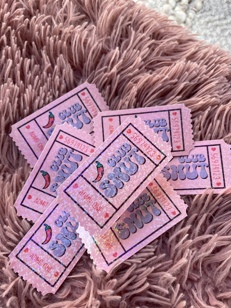 May include: Pink glittery tickets with the text "Club Shut" and a chili pepper graphic. Each ticket has a unique number and the words "Admit One". The tickets are scattered on a fluffy, pink surface.