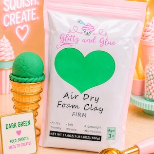 May include: A white pouch of Glittz and Glue Air Dry Foam Clay in firm dark green. The packaging features a large green heart, text including 'Air-dry', 'Soft', 'Lightweight', 'Stretchy', 'Pliable', 'No Residue', and 'NET WT 17.6OZ(1LB1.6OZ)(500g)'.