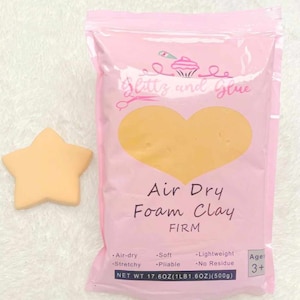 May include: A pink bag of air dry foam clay labeled "Glitzy and Glue Air Dry Foam Clay Firm". The bag is on a white fuzzy surface. The clay is a light yellow color. The bag has a net weight of 17.6 ounces (1 pound 1.6 ounces) or 500 grams. The bag is labeled for ages 3 and up.