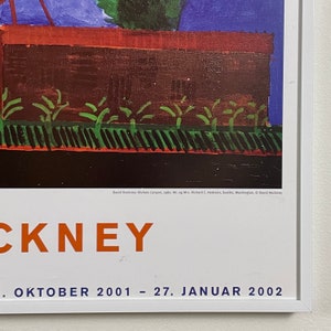 May include: A poster advertising an exhibition of David Hockney's work. The poster features a painting of a house with a red roof and green bushes in front of it. The text on the poster reads "David Hockney: Nichols Canyon, 1980. Mr. og Mrs. Richard C. Hedreen, Seattle, Washington, &copy; David Hockney" and "CKNEY . ОКТО&Beta;ER 2001 - 27. JANUAR 2002".