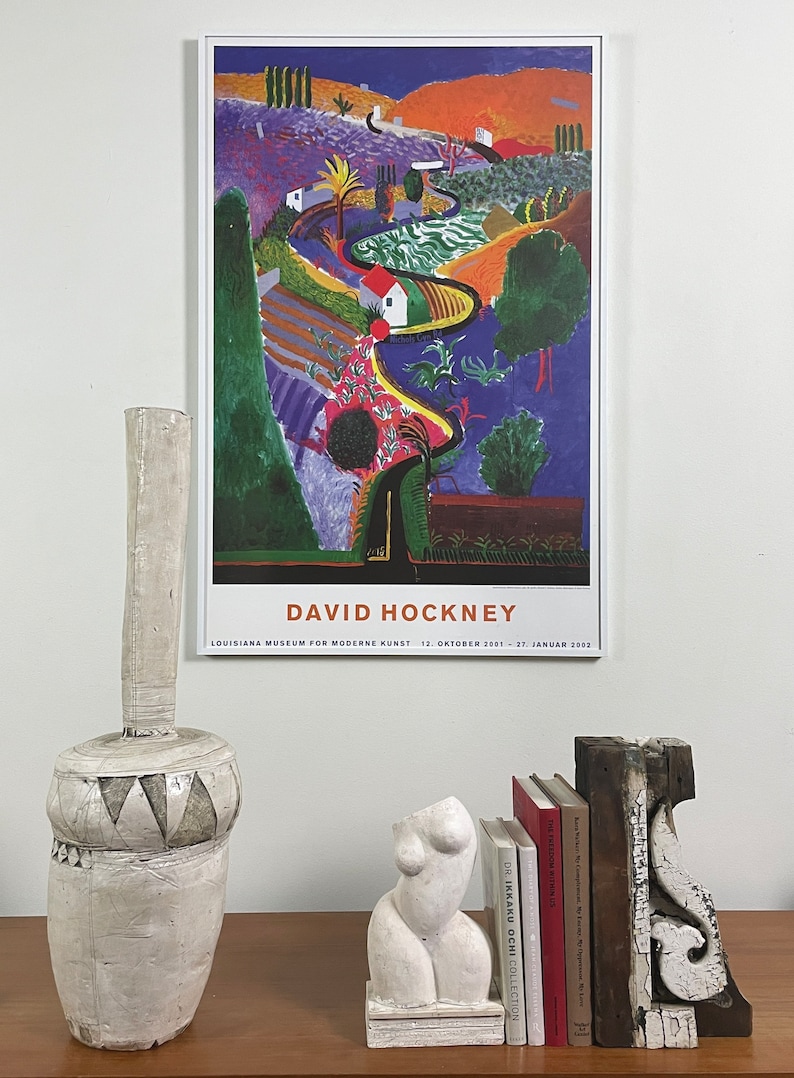 May include: A poster of a painting by David Hockney, featuring a colorful landscape with a winding road, trees, and houses. The poster is titled "David Hockney" and includes the text "Louisiana Museum for Moderne Kunst 12. Oktober 2001 - 27. Januar 2002".