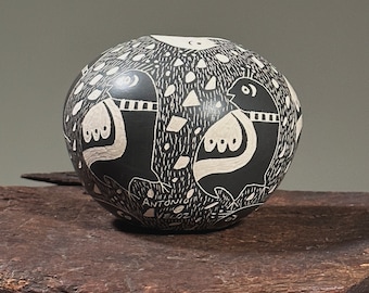 Puede incluir: Olla de cerámica negra y blanca con forma redonda y un diseño de pájaros y formas abstractas. La olla está firmada "Antonio Veloz".