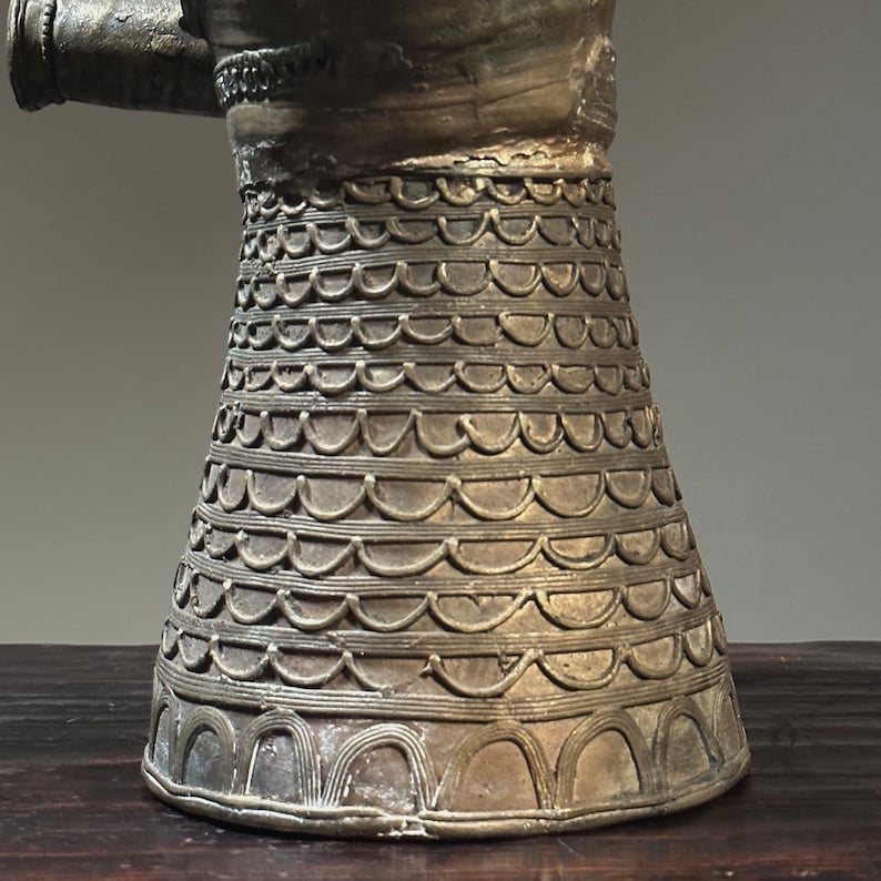 May include: A gold-colored metal pitcher with a decorative pattern of overlapping semicircles around the base.