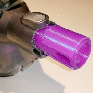 Könnte beinhalten: Nahaufnahme eines violetten Aufsatzes aus Kunststoff für einen Staubsauger. Der Aufsatz hat eine runde Öffnung und ein kleines Loch an der Seite.