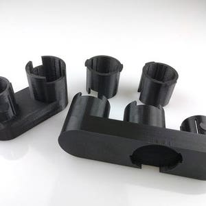 May include: A set of black plastic 3D printed organizers for small items. The organizers are designed to hold small items like pens, pencils, or other office supplies.