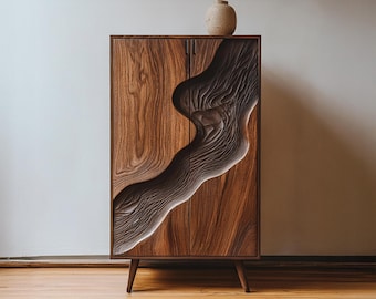 May include: A tall, wooden cabinet with a carved, flowing design on the front doors. The cabinet is made of dark brown wood and has a light brown carved accent. A small, tan vase sits on top. The cabinet has four legs.