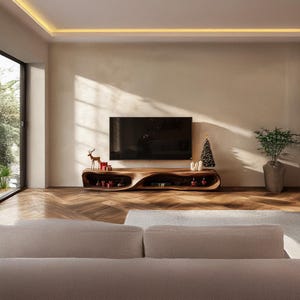 Puede incluir: Un salón moderno con un televisor de pantalla plana grande sobre una consola de medios de madera de forma orgánica única. La consola tiene estanterías abiertas y está decorada con adornos navideños. Un pequeño árbol de Navidad y una planta en maceta completan la decoración.