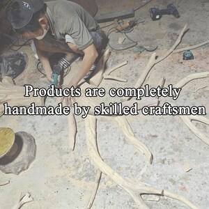K&ouml;nnte beinhalten: Ein Handwerker bearbeitet eine Holzskulptur mit einem Elektrowerkzeug. Der Text im Bild lautet: "Produkte werden komplett von erfahrenen Handwerkern handgefertigt."