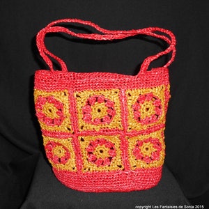 Peut inclure: Un sac fourre-tout en crochet rouge et or avec un motif carré. Le sac a deux anses et est fait d'un matériau tissé.