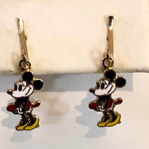 May include: Gold-coloured leverback earrings. Each earring features a cartoon mouse character with black ears, a white face, a red jacket, and yellow shoes. A classic design for Disney fans.
