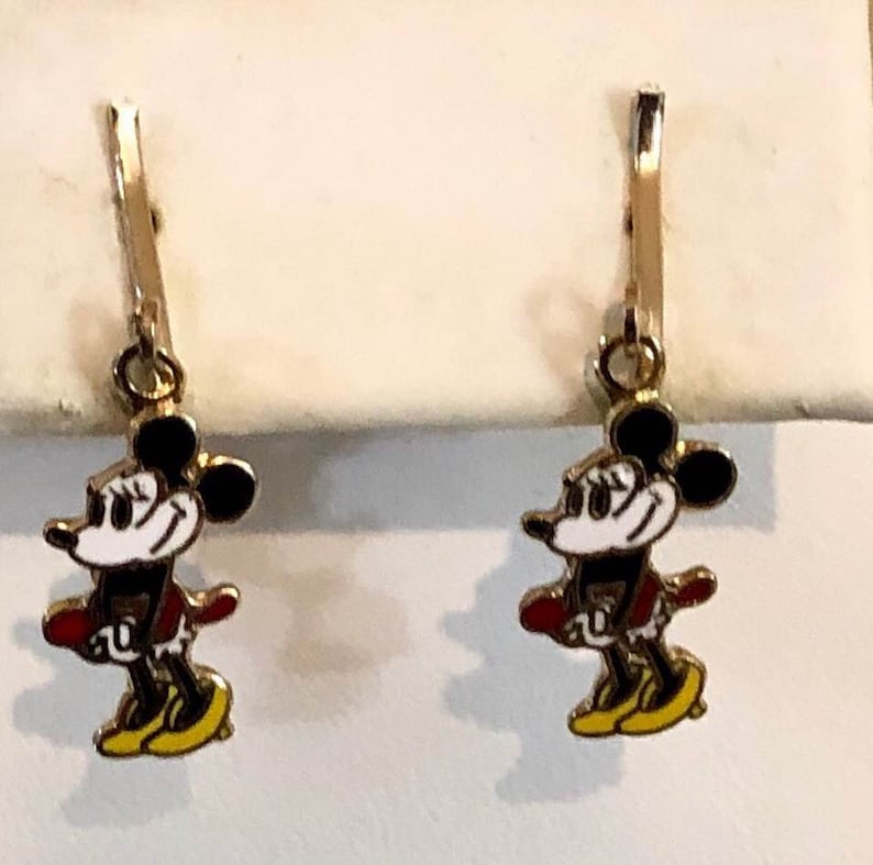 May include: Gold-coloured leverback earrings. Each earring features a cartoon mouse character with black ears, a white face, a red jacket, and yellow shoes. A classic design for Disney fans.
