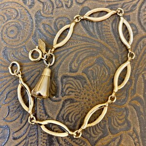 May include: A gold-toned bracelet with a teardrop-shaped charm. The bracelet is made of oval-shaped links and has a lobster claw clasp.