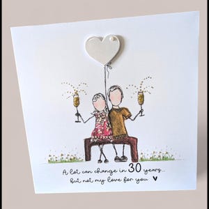 May include: A square greeting card featuring a hand-drawn illustration of two figures sitting on a bench, holding gold glitter champagne flutes. Above them is a white heart balloon. Text reads: A lot can change in 30 years... but not my love for you.