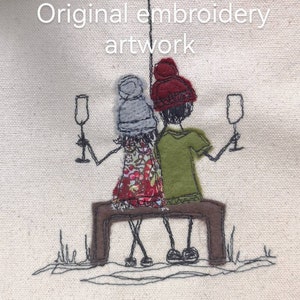 May include: this is the original embroidered artwork depicting two figures seated on a bench, each holding a glass of champagne.