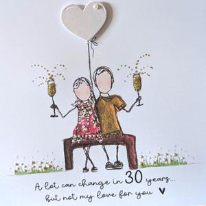 May include: A greeting card featuring a line-art illustration of two figures sitting on a bench, holding gold glitter champagne flutes. Above them is a white heart balloon. The text reads: A lot can change in 30 years... but not my love for you.