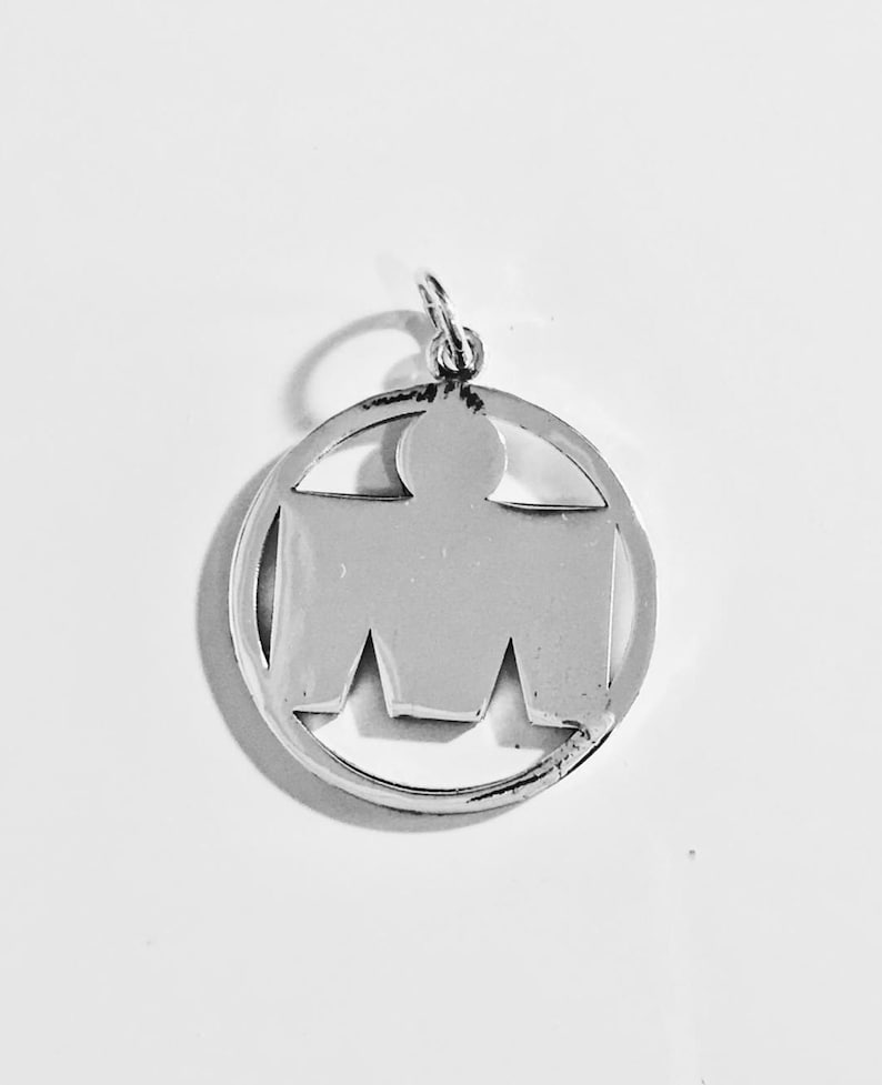 May include: Silver charm pendant featuring a stylized human figure inside a circle. The figure is solid silver, while the circle is outlined in silver.