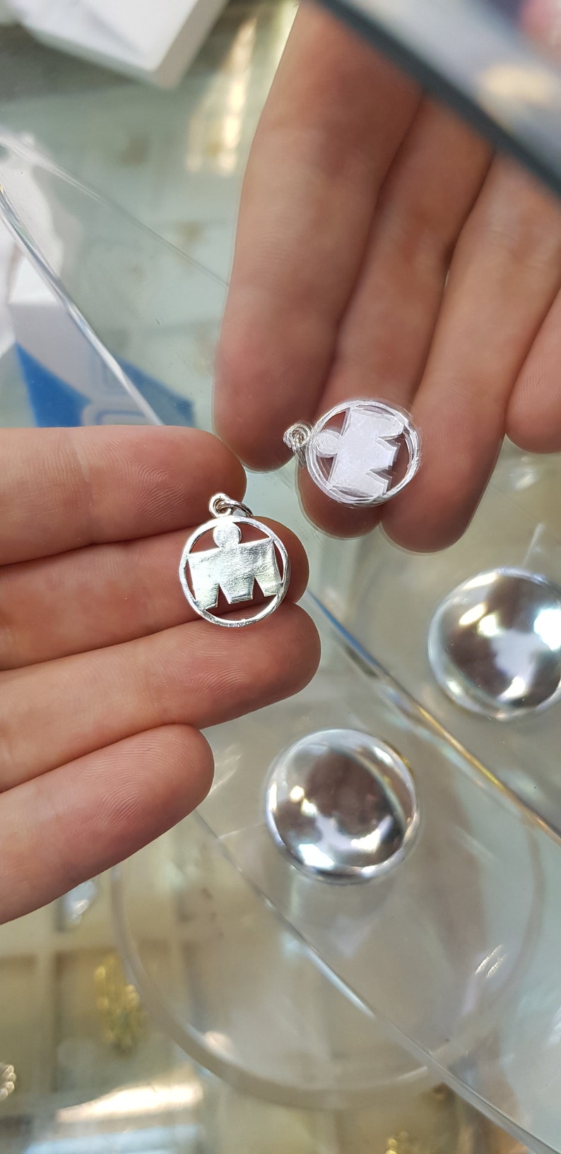 May include: Two silver charms in the shape of a running person, a popular symbol for marathon runners. The charms are round and have a smooth, polished finish.