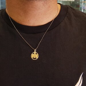 May include: A gold chain necklace with a round pendant featuring a stylized letter M.