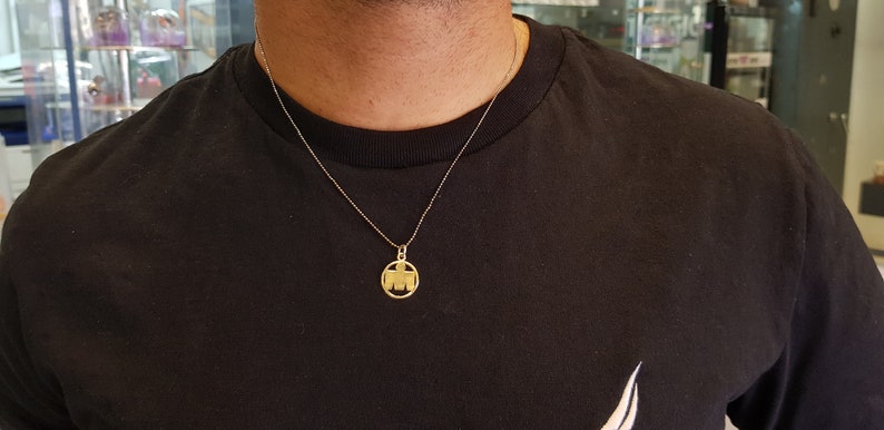 May include: A gold chain necklace with a round pendant featuring a stylized letter M.