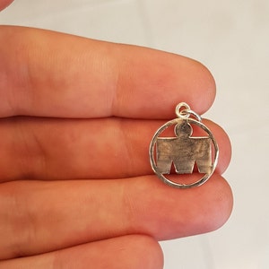 May include: Silver charm with a stylized human figure inside a circle.