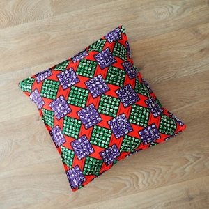 Peut inclure: Coussin décoratif rouge, vert et violet avec un motif en losange.