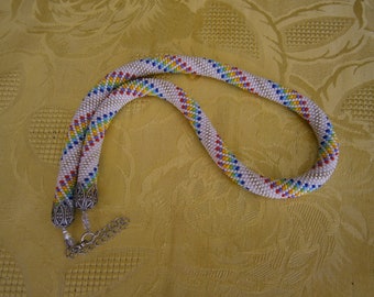 Collier en perles de rocaille réalisé AU CROCHET sur fond blanc et aux couleurs de l'arc-en-ciel