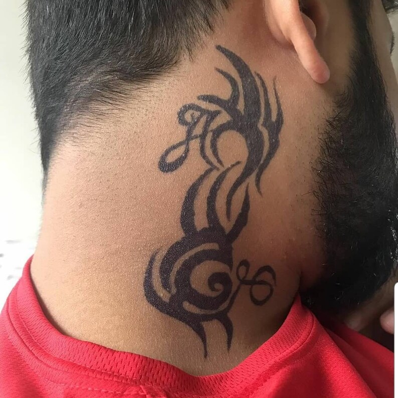 Puede incluir: Un tatuaje tribal negro en la parte posterior del cuello de una persona.