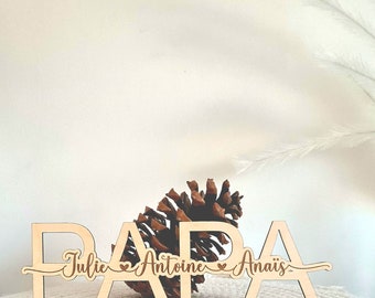 May include: Wooden sign with the word "PAPA" in large letters, with the names "Julie", "Antoine", and "Anais" written below, each with a small heart symbol between them.