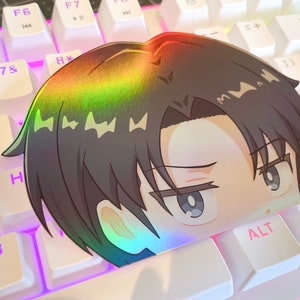 May include: A holographic sticker featuring an anime character with brown hair and blue eyes. The character is looking to the right with a serious expression. The sticker is placed on a white keyboard with pink lighting.